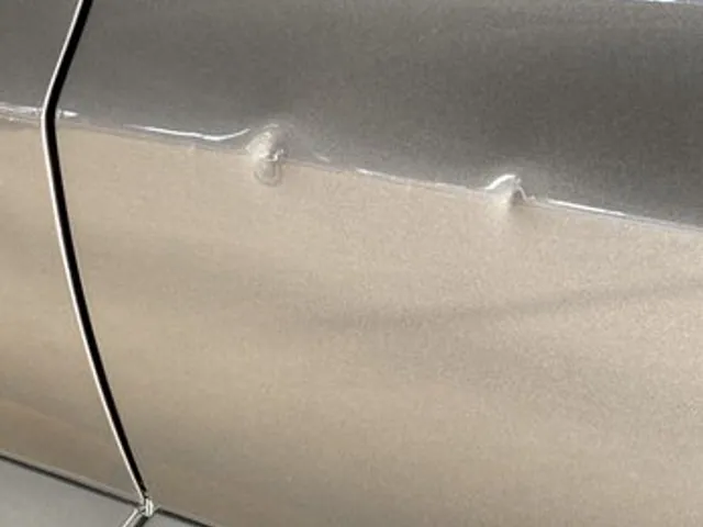 Dent on a champagne sedan panel before paintless dent repair