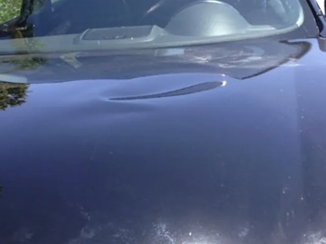 Crease on a dark sedan panel before repair