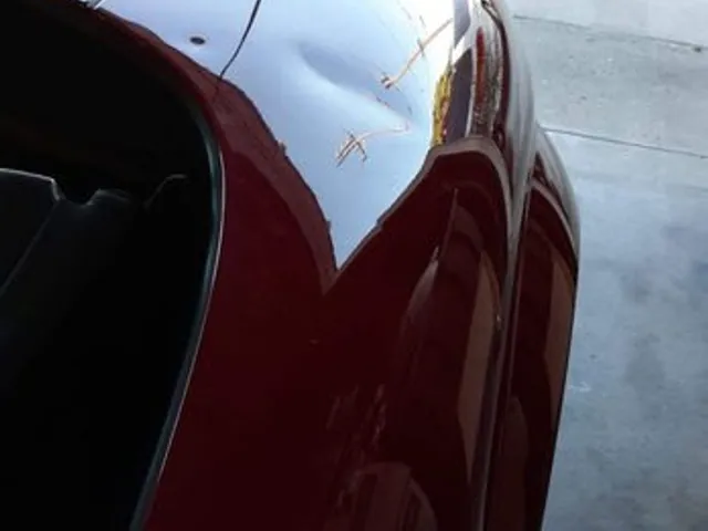 Damage on a red car rear quarter panel before repair