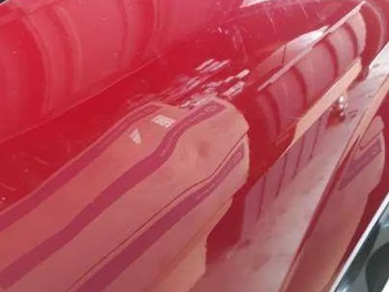 Red coupe with a crease on the body line before repair